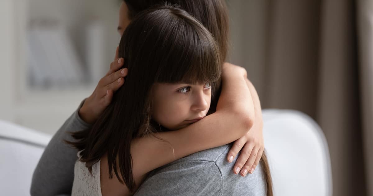 üzgün küçük bir kız evde annesine sarılıyor